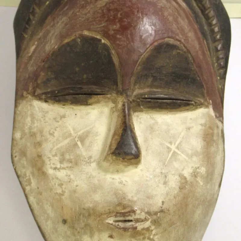 African tribal mask in red and white with X pattern, hand-carved wooden mask